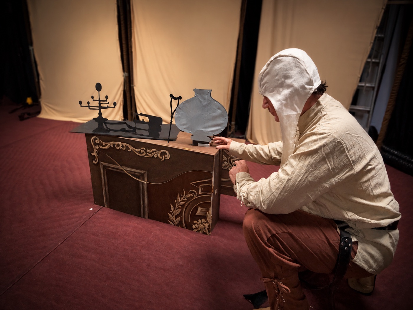 José Diego Ramírez agachado junto a la mesa escenográfica, probando la manipulación de El Diablo Cojuelo.