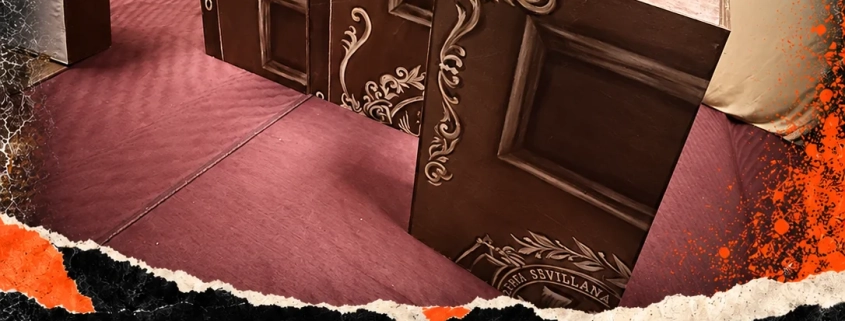 Cajas escenográficas, un pop-up y pantallas de El Diablo Cojuelo sobre el suelo rojizo. Diario de creación #15: La escena toma cuerpo.